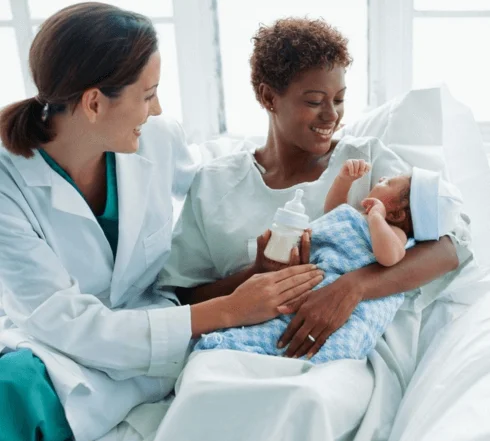 Picture of a woman holding a newborn in her arms with a doctor next to her