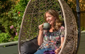 Picture of a person living with a severe disease enjoying a cup of coffee in her garden